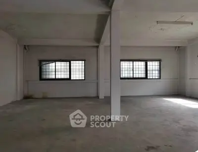 Spacious industrial-style room with large windows and concrete flooring, ideal for creative workspace or studio.