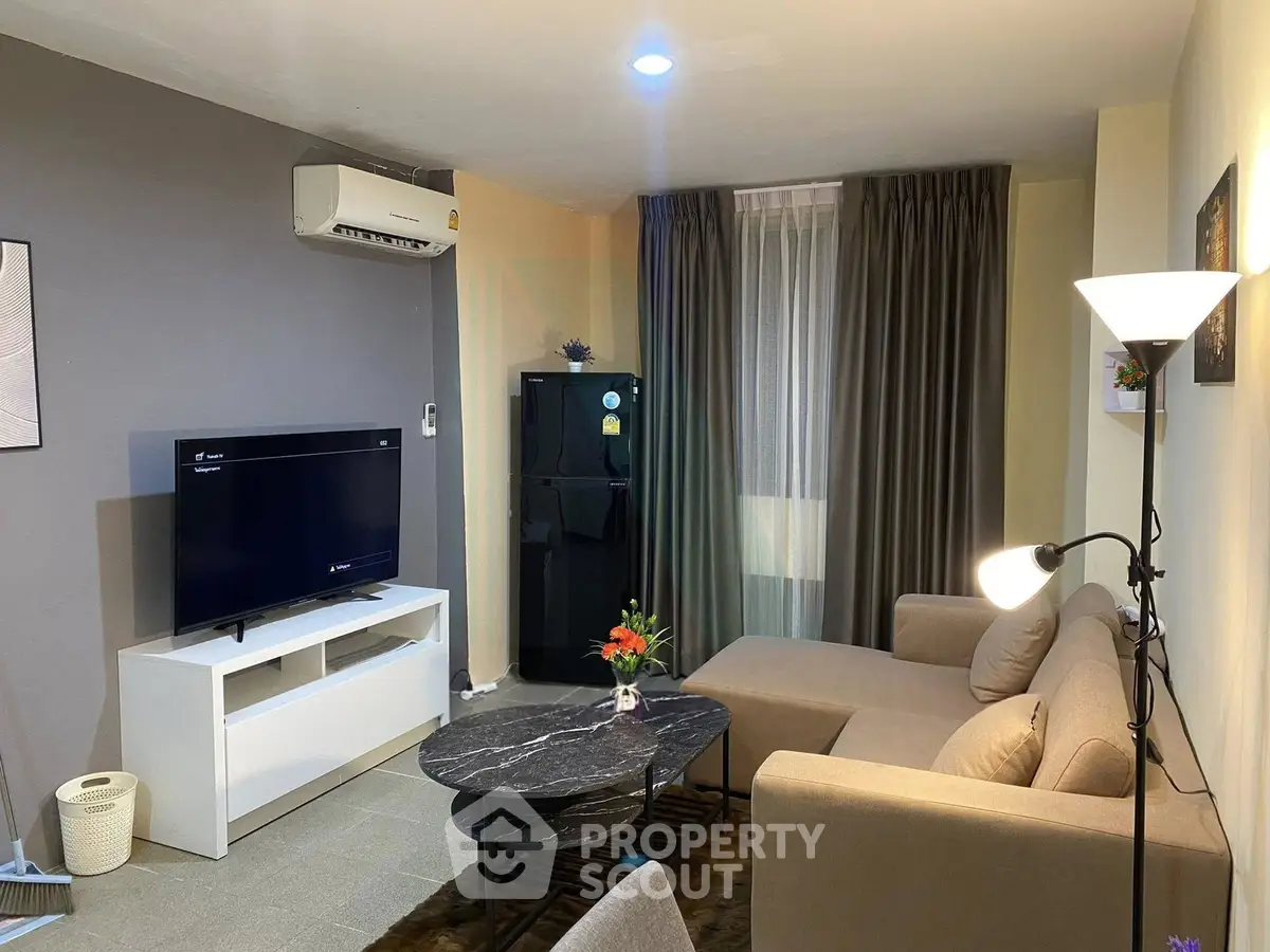 Modern living room with stylish furniture and air conditioning, featuring a cozy sofa and flat-screen TV.