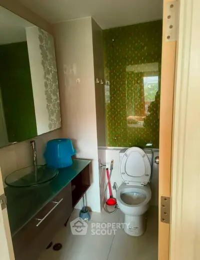 Modern bathroom with unique green wallpaper and glass sink