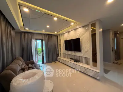 Luxurious living room with modern decor and large TV, featuring elegant marble wall and cozy seating area.
