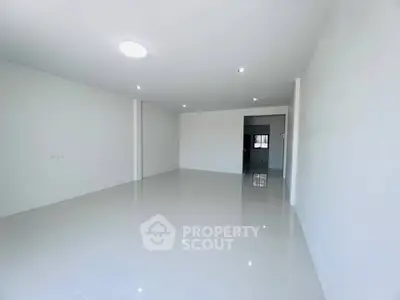 Spacious empty room with glossy white tiles and recessed lighting, perfect for customization.
