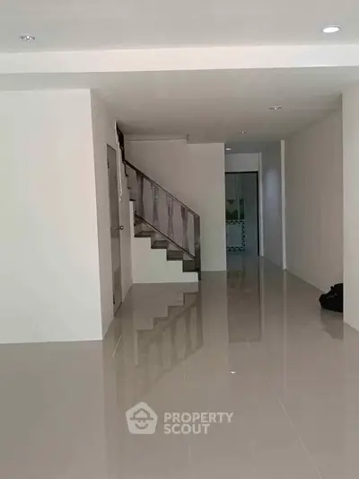 Spacious modern interior with sleek staircase and glossy tiled flooring, perfect for contemporary living.