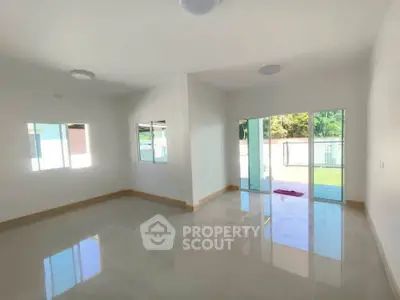 Spacious living room with large windows and sliding glass doors opening to a garden view.