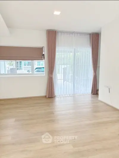 Spacious empty living room with large windows and elegant curtains