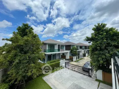 Luxurious modern villas with lush greenery and clear blue sky in a serene neighborhood.