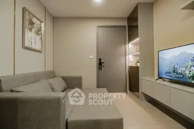Modern living room with sleek gray sofa and wall-mounted TV in stylish apartment.