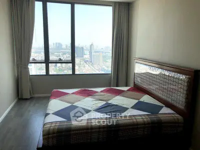 Spacious bedroom with large window offering stunning city views, perfect for urban living.
