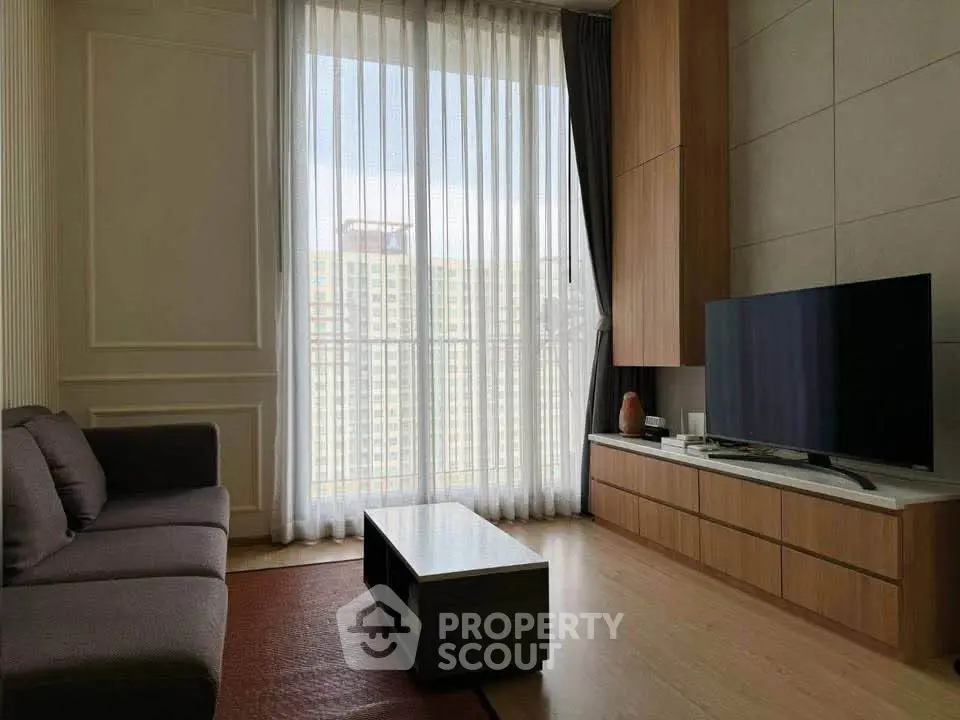 Modern living room with large window and city view, featuring sleek furniture and a flat-screen TV.