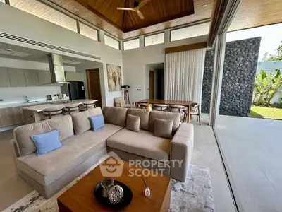 Luxurious open-plan living room with modern kitchen and garden view, featuring high ceilings and elegant decor.