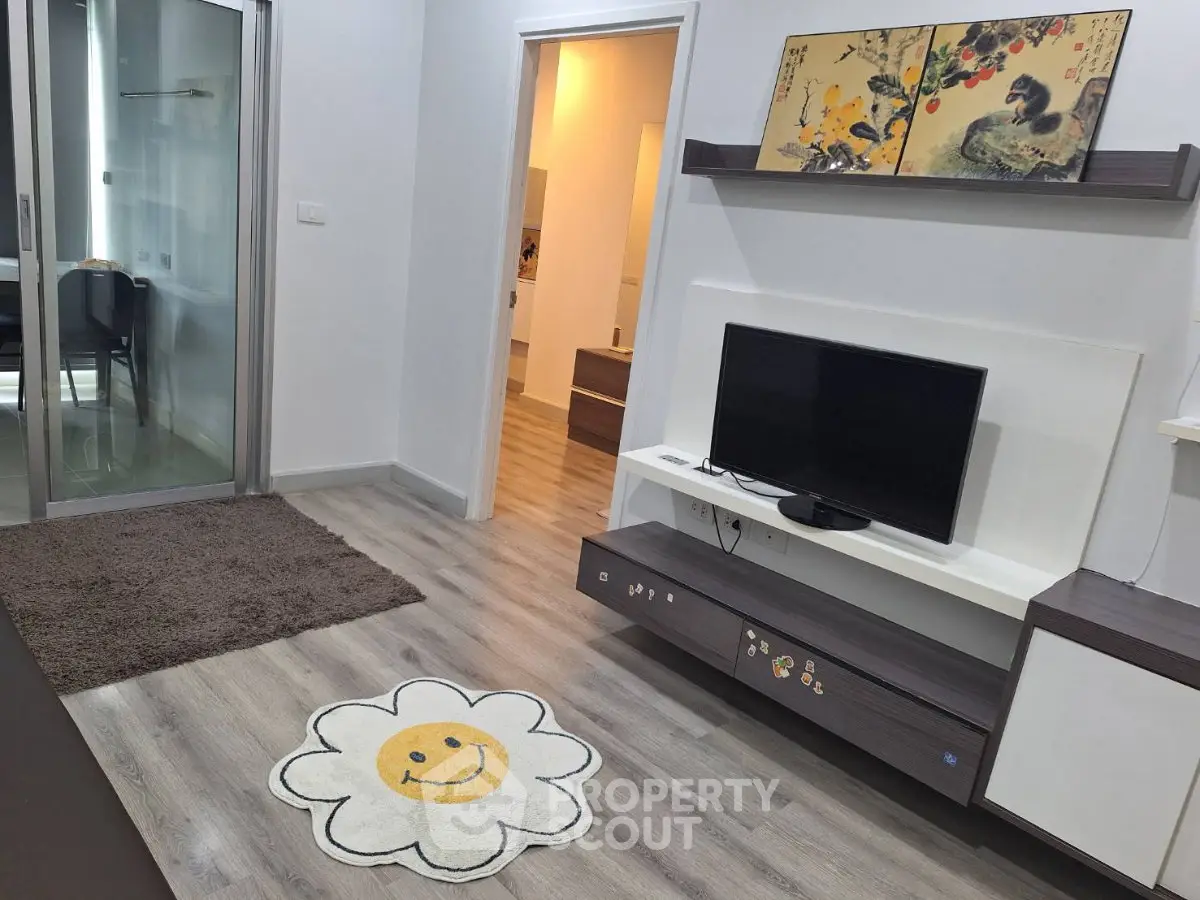 Modern living room with stylish decor and open layout, featuring a TV and artistic wall art.