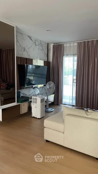 Modern living room with stylish decor and large TV, featuring elegant curtains and a cozy sofa.