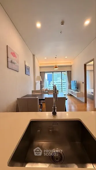 Modern open-plan living room with city view, featuring sleek kitchen sink and stylish decor.