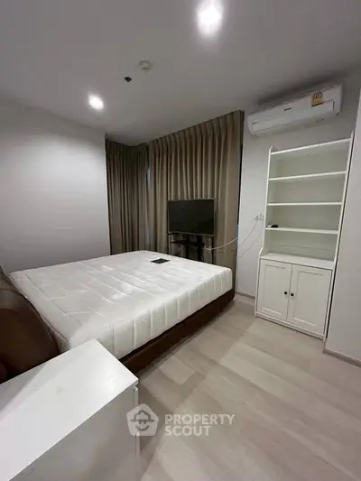 Modern bedroom with sleek design, featuring a comfortable bed, built-in shelves, and air conditioning.