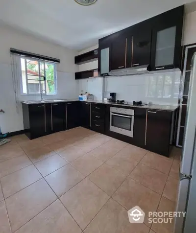 Spacious modern kitchen with sleek black cabinets and built-in oven, perfect for culinary enthusiasts.