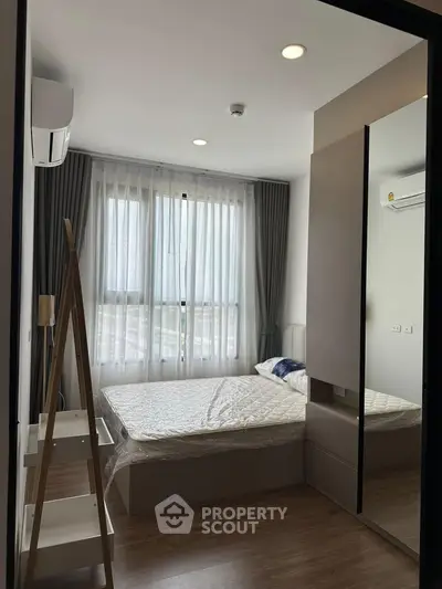 Modern bedroom with large window and stylish decor in a contemporary apartment.