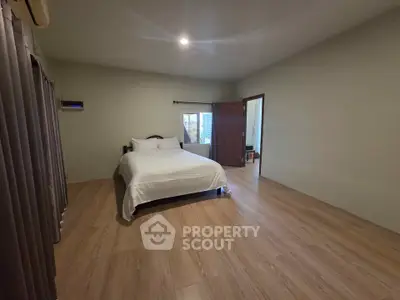 Spacious bedroom with wooden flooring and cozy ambiance