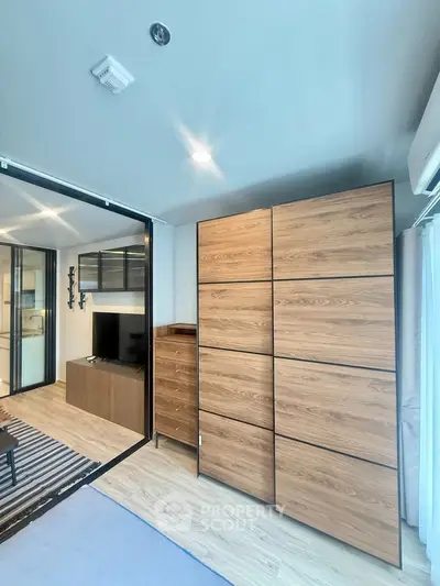 Modern living room with wooden furniture and sliding glass doors in a stylish apartment.