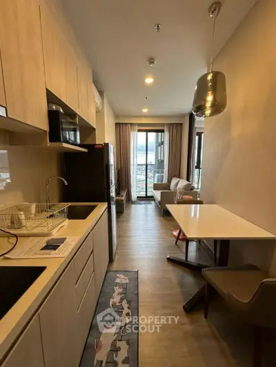 Modern open-layout kitchen and living area with stylish decor and balcony view.