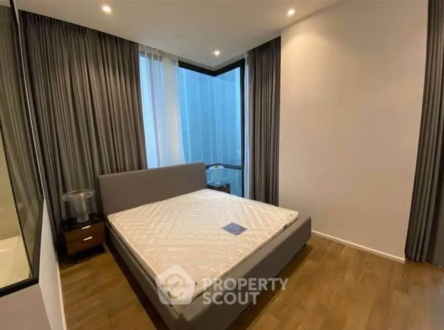 Modern bedroom with large windows and elegant curtains in a high-rise apartment.