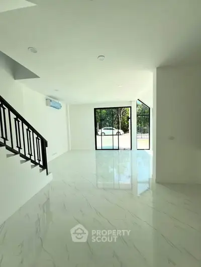 Spacious modern living room with glossy marble floors and large glass doors opening to a garden view.