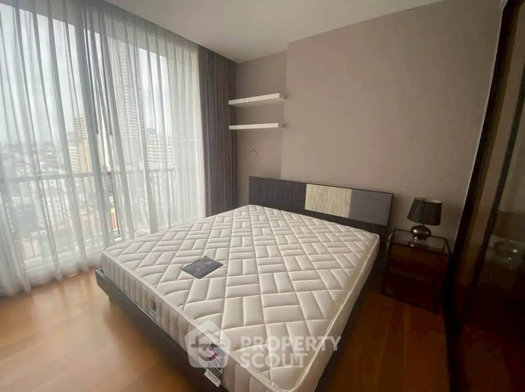 Spacious bedroom with large window offering city view and modern furnishings.