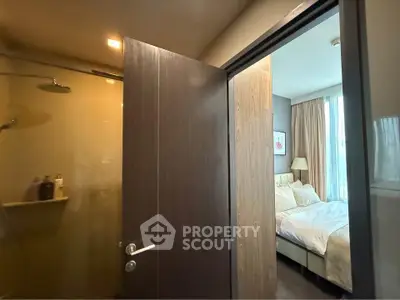 Modern bedroom with ensuite bathroom featuring glass shower door and cozy decor.