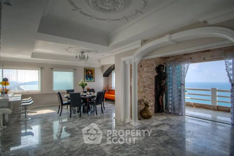 Luxurious open-plan living room with ocean view and elegant marble flooring.