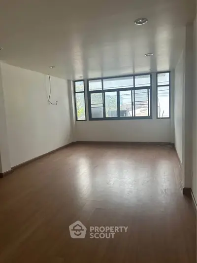 Spacious empty room with large windows and wooden flooring, ideal for customization.