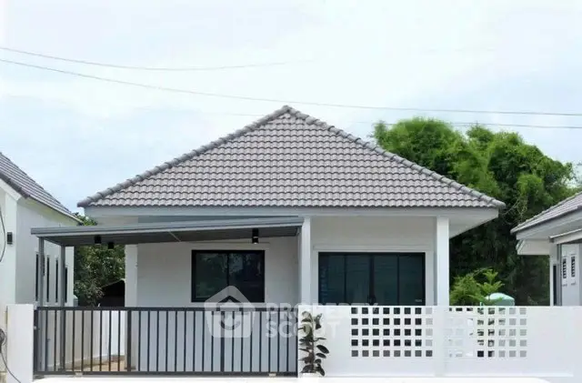 Charming single-story house with tiled roof and modern fence in a serene neighborhood.