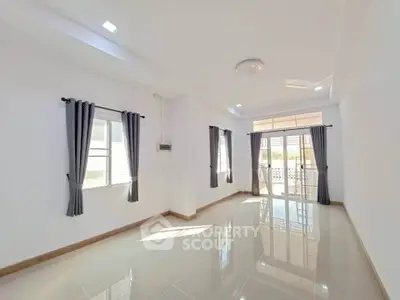 Spacious sunlit living room with large windows and modern tile flooring.