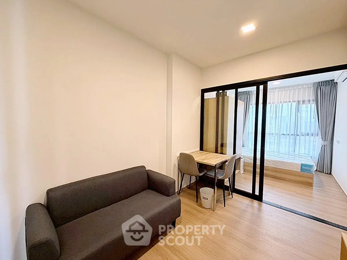 Modern apartment interior with cozy living room and bedroom separated by glass doors.