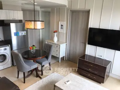 Modern living room with dining area, wall-mounted TV, and compact kitchen featuring washing machine.