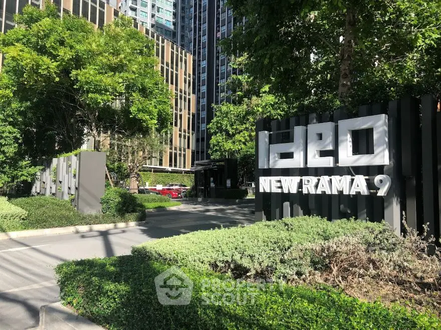 Modern condominium entrance with lush greenery at Ideo New Rama 9.