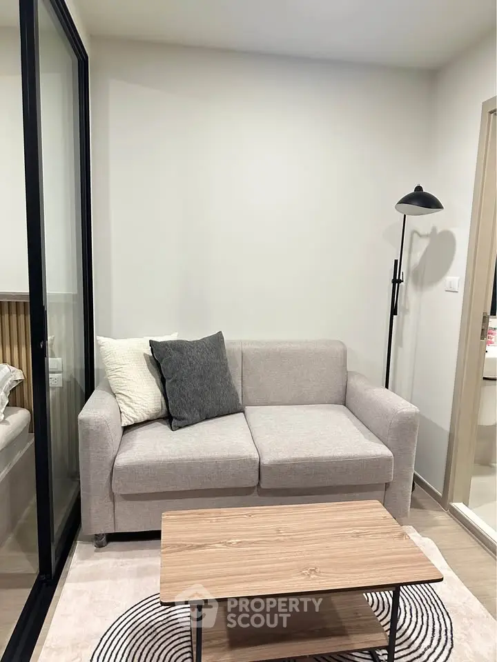 Modern living room with cozy sofa and stylish decor in a compact apartment setting.