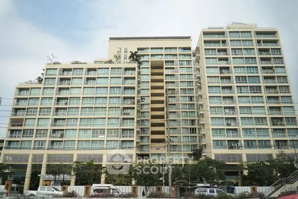 Modern high-rise residential building with large windows and balconies in urban setting.