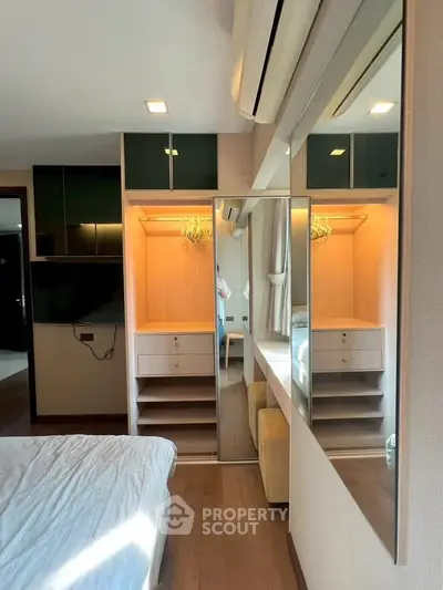 Modern bedroom with mirrored wardrobe and sleek wooden flooring