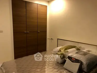 Cozy bedroom with wooden wardrobe and neatly made bed in modern apartment.