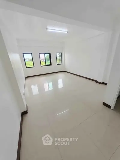 Spacious empty room with large windows and glossy tiled floor, perfect for customization.