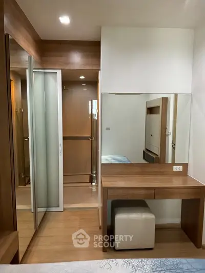 Modern bedroom with wooden accents and mirrored wardrobe in cozy apartment.