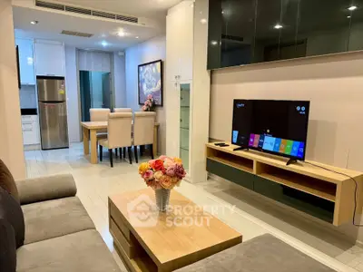 Modern living room with open kitchen, stylish furniture, and smart TV, perfect for contemporary living.
