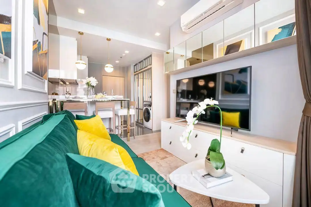 Modern living room with green sofa, stylish decor, and open kitchen layout in a contemporary apartment.