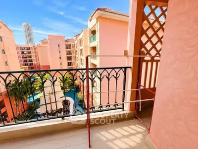Charming balcony with wrought iron railing overlooking a vibrant residential complex and pool.