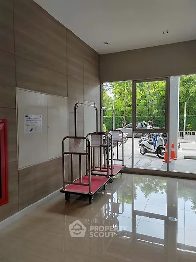 Modern building entrance with luggage carts and large windows offering a view of the street.