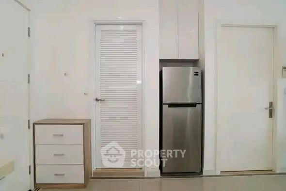 Modern kitchen area with sleek stainless steel fridge and minimalist cabinetry.