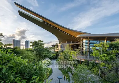 Stunning modern building with unique architecture surrounded by lush greenery and city skyline views.