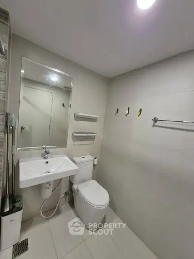 Modern bathroom with sleek fixtures and minimalist design, featuring a white sink and toilet.