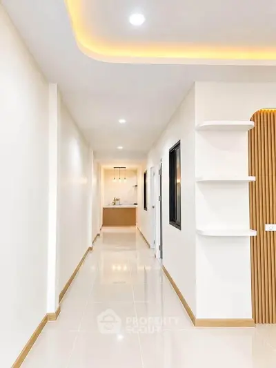 Modern hallway with sleek design and ambient lighting leading to a stylish kitchen area.