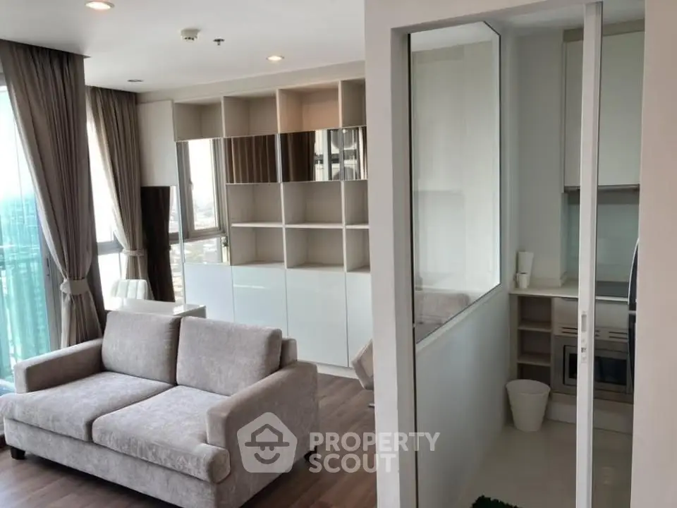 Modern living room with elegant sofa and stylish shelving, adjacent to a compact kitchen area.