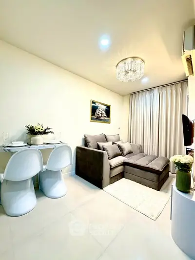 Modern living room with elegant chandelier and cozy gray sofa, perfect for relaxation and entertainment.