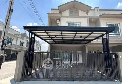 Modern townhouse with spacious gated driveway and sleek metal carport in a suburban neighborhood.